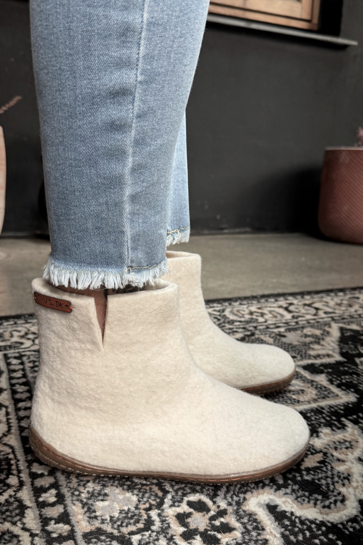 SHUS.dk beige håndlavede uldstøvler med højt skaft og gummisål, vist på fødder i jeans.